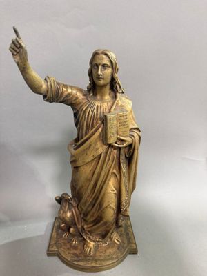 statue en bronze représentant une femme tenant un livre et pointant le ciel du doigt