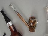 a bottle of beer, a pipe, and a pipe holder on a table