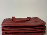three red leather bags stacked on top of each other on a white surface