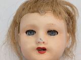 a close up of a doll with blue eyes and blonde hair