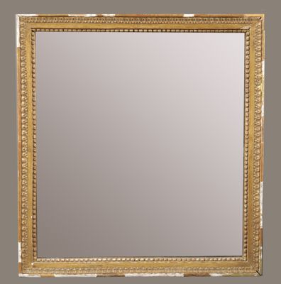 un miroir à cadre doré accroché à un mur avec un encadrement en bois