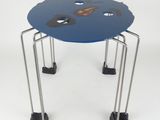 une petite table bleue à quatre pieds, sur laquelle se trouve une horloge
