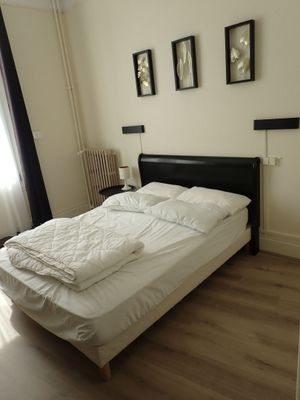 un lit avec des draps blancs et une tête de lit noire