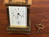 une petite horloge posée sur une table en bois, à côté d'une paire de ciseaux