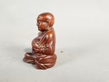 an image of a small statue of a person sitting on a white surface
