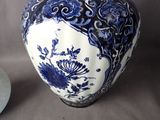 a blue and white vase sitting on a table next to a plate