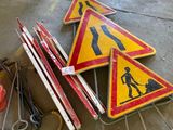 a pile of construction signs on the ground next to a car