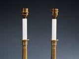 a pair of brass candles with white candlesticks on them