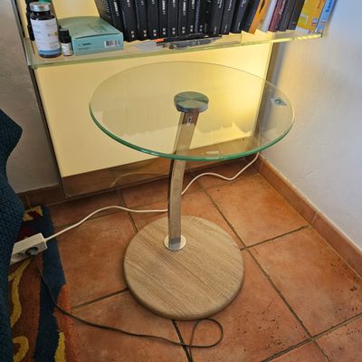 une table avec un plateau en verre et une bibliothèque remplie de livres