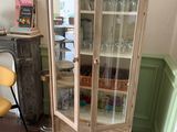 a cabinet with a glass door in the corner of a room