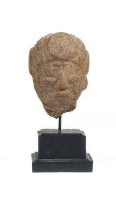 statue représentant la tête d'un homme posée sur un socle, sur fond blanc