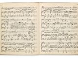 un livre ouvert, orné de notes de musique, posé sur une surface blanche