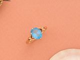 une image représentant une bague en or surmontée d'une pierre bleue