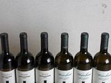 six bottles of wine are lined up on a wooden table