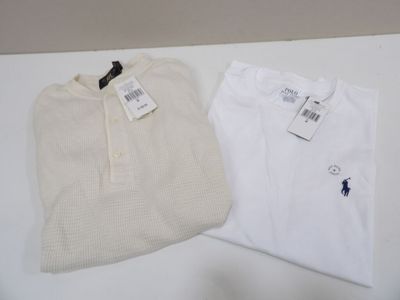 two white shirts are sitting on a table with tags on them