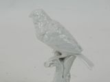 porcelain figurine of a bird on a branch with a white background