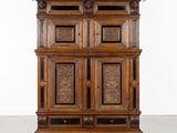 une vieille armoire en bois avec des portes sculptées et des tiroirs montés sur roulettes
