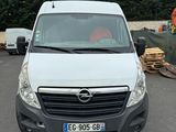 La camionnette blanche est garée sur le parking, à côté d'un tas de bois