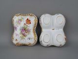 two pieces of porcelain with floral designs on them on a gray surface