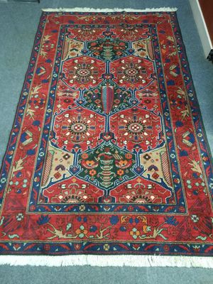 Le tapis posé au sol est rouge et bleu, avec un motif floral.