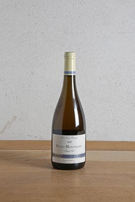 une bouteille de vin posée sur une table, avec un mur blanc en arrière-plan