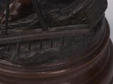 bronze statue of a man in a boat on a wooden base