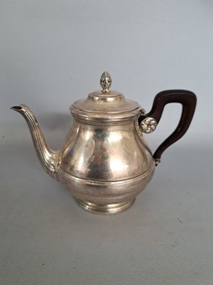 une théière ancienne en argent, munie d'une poignée en bois, posée sur une table