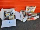 deux cartons contenant des objets divers, posés par terre à côté d'un mur orange