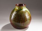 un vase vert et rouge posé sur une surface blanche