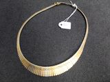 necklace made of gold colored metal with a white tag on a black surface