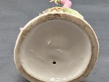 a white vase with a pink flower on top of it