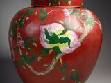 un vase rouge sur lequel est peinte une fleur