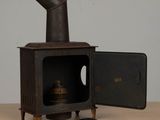 an old fashioned stove with a metal door open on a wooden table