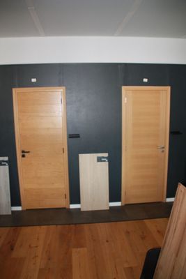 three wooden doors in a room with black walls