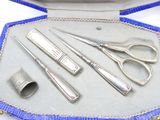 a silver case with scissors, a needle, and a thimble