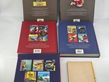 three books of comics are lined up on a white surface