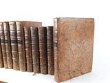 several old books are lined up on a shelf next to each other