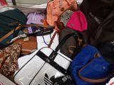 a pile of purses and handbags sitting on a bed