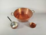 une casserole en cuivre avec une louche et une cuillère doseuse