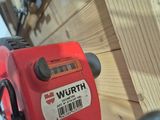 a close up of a red cordless drill on a wooden fence