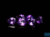 a close up of a group of purple gems on a black surface