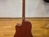 an acoustic guitar sits on a stand in front of a computer desk