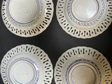 four blue and white plates on a table with a black background