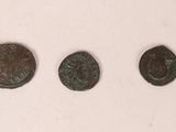 three bronze coins are shown in a row on a white surface