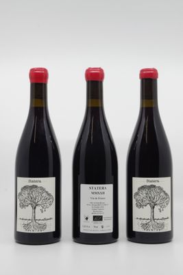 trois bouteilles de vin rouge sont alignées sur une surface blanche