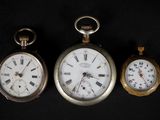 Trois types différents de montres de poche sont exposés sur un fond noir