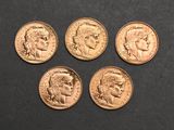 four different types of gold coins on a black surface