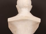 a white marble bust of a man on a wooden table
