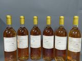 six bouteilles de vin sont alignées sur une surface grise