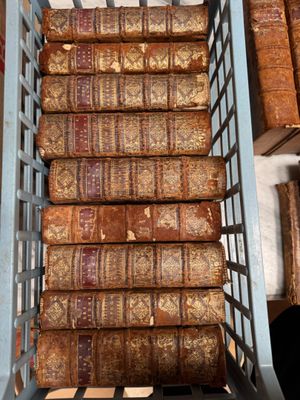 a basket full of old books sitting on a shelf